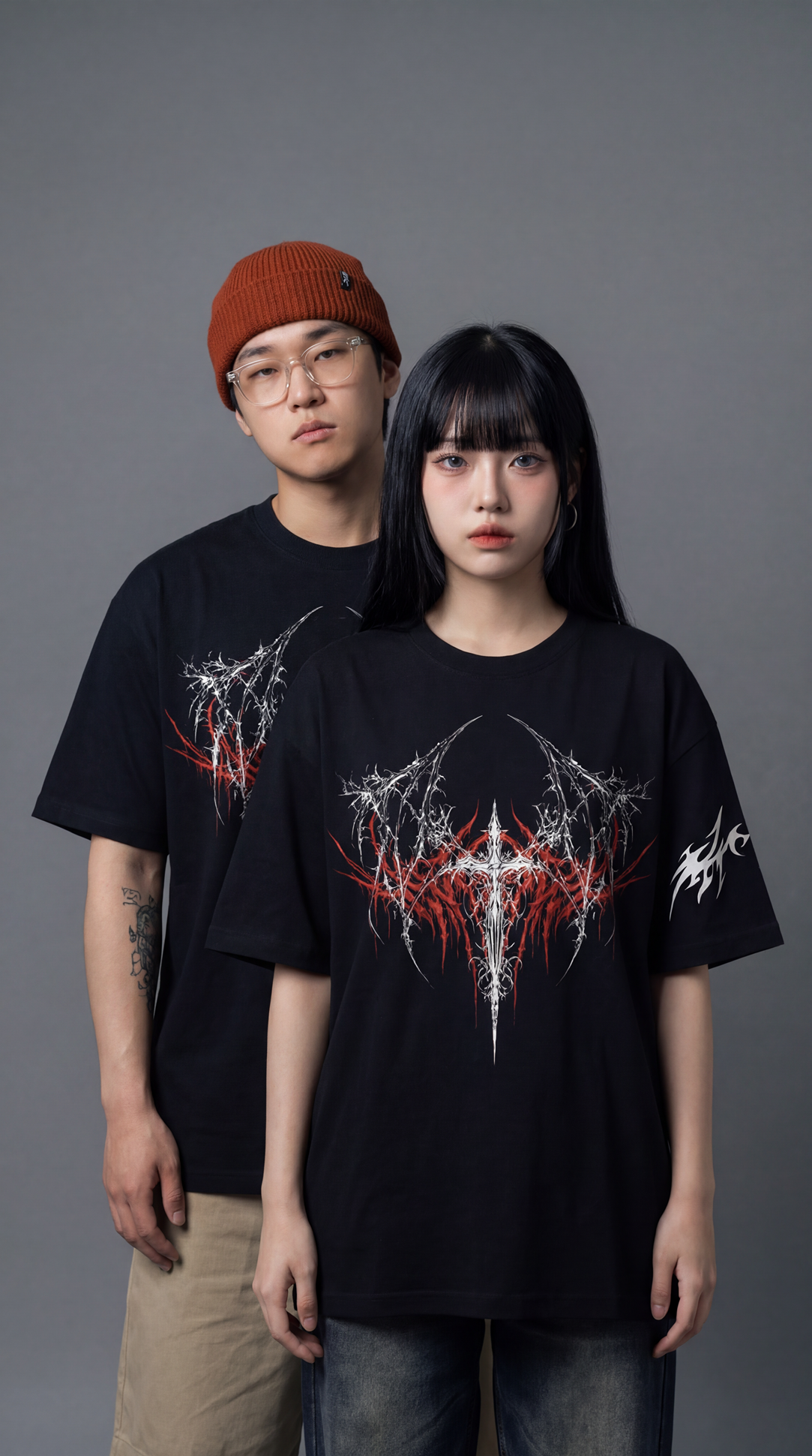 Two people wearing black t-shirts with a graphic design on a gray background