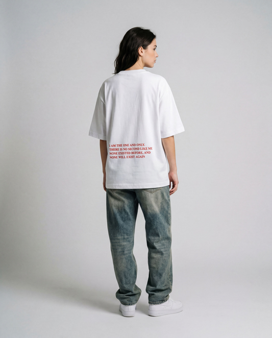 Person wearing a white t-shirt with text on the back and blue jeans against a plain background