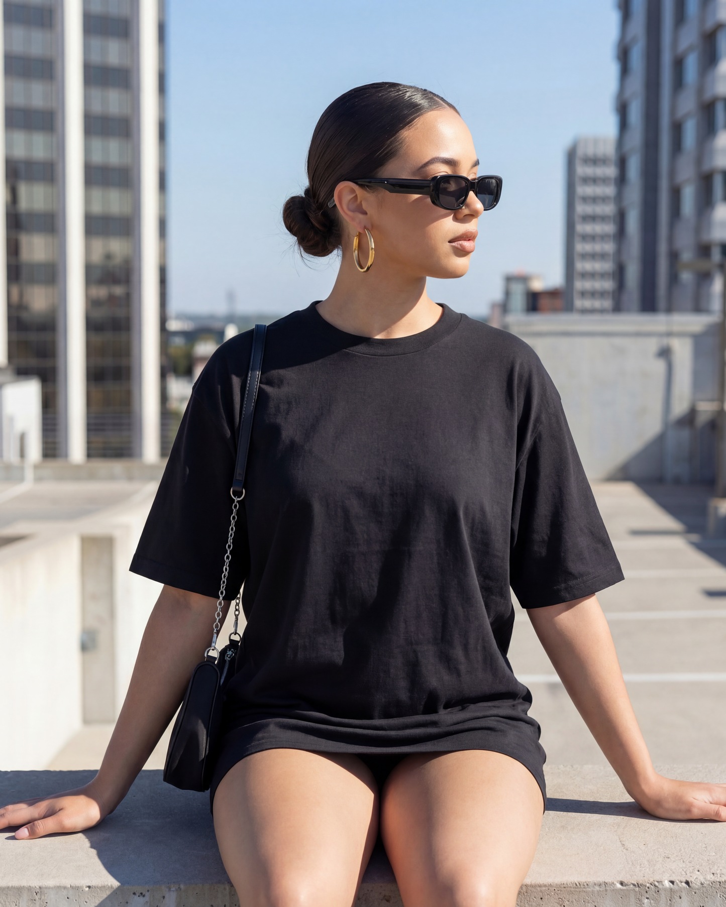 Woman in a black outfit sitting on a rooftop with cityscape background