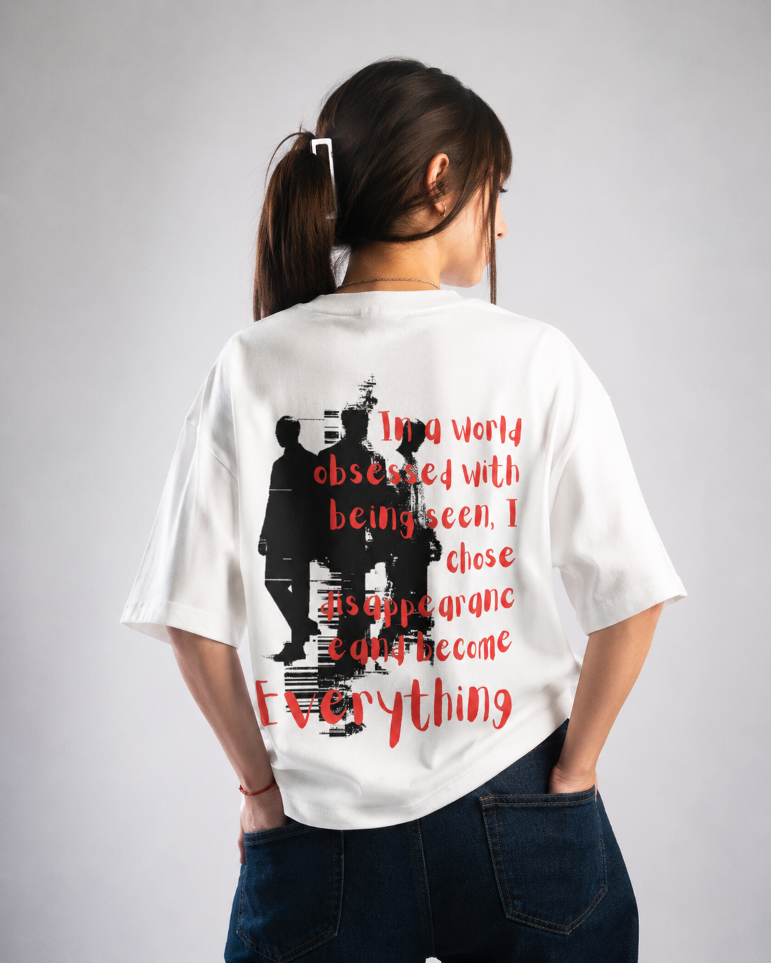 Person wearing a white t-shirt with red text and black graphic on the back, standing against a plain background.