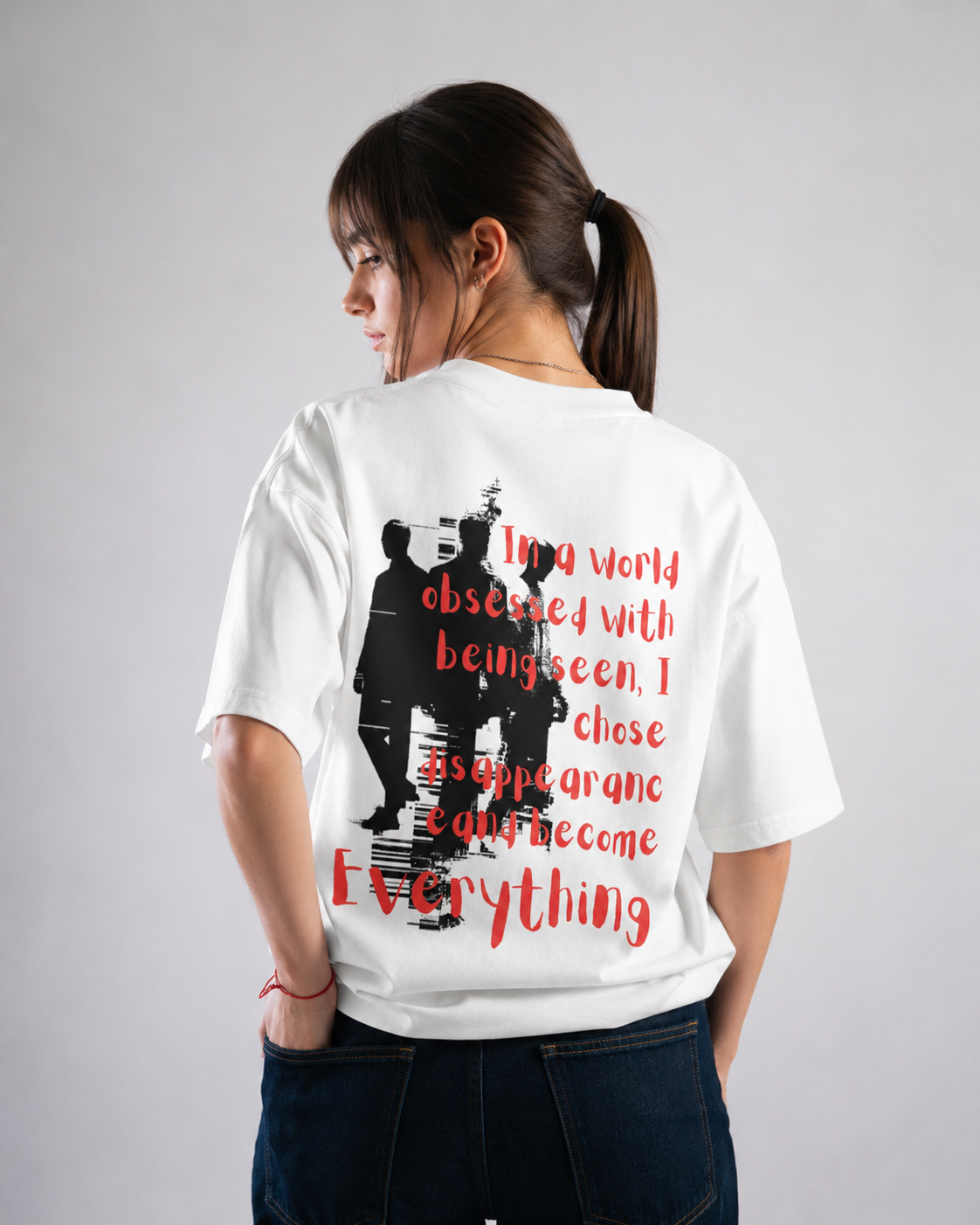 Person wearing a white t-shirt with a graphic and text on the back, standing against a plain background.