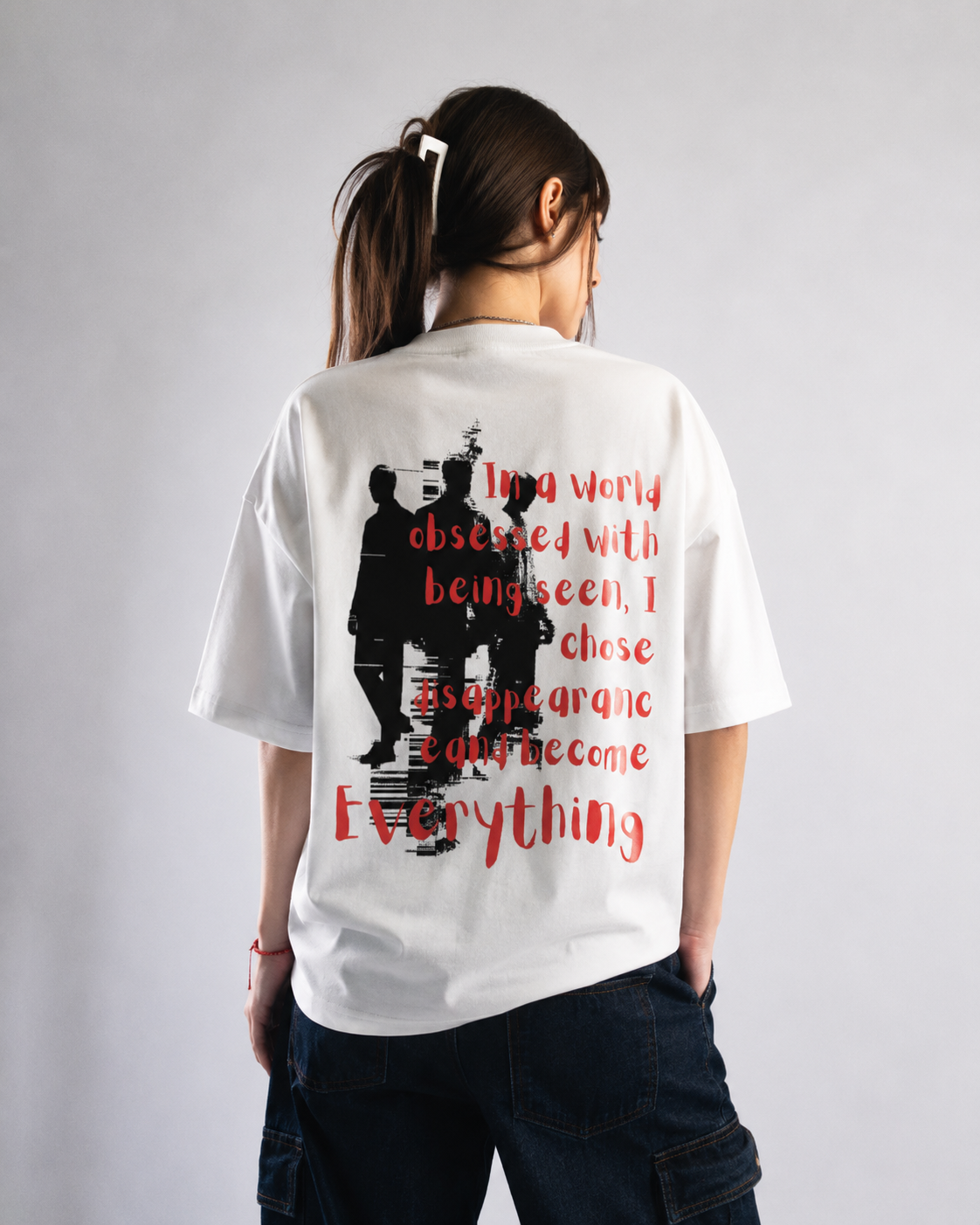 Person wearing a white t-shirt with black and red graphics and text on the back.