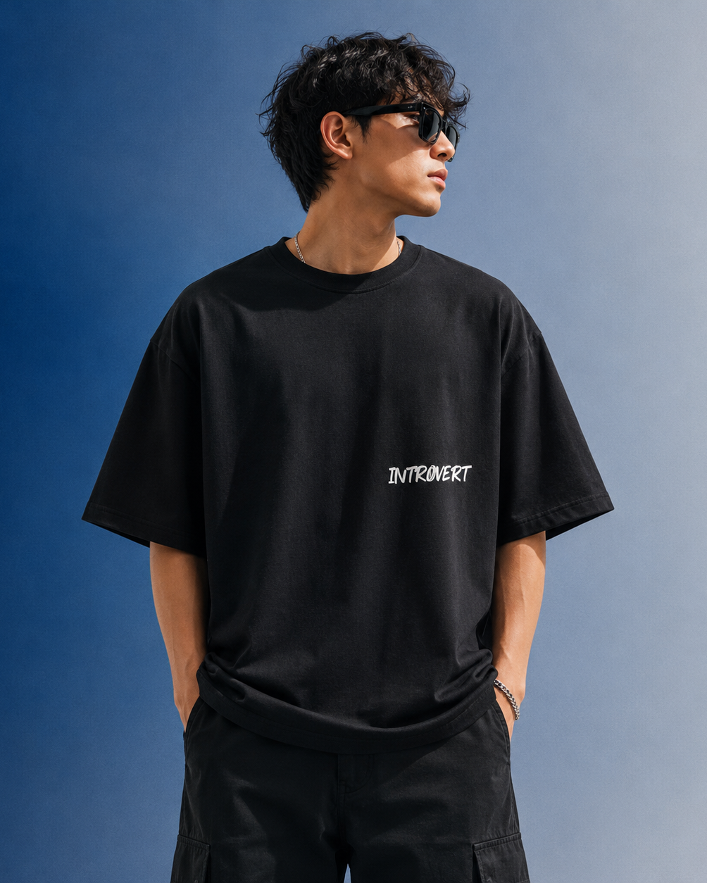Person wearing a black t-shirt with 'INTROVERT' text against a blue sky.